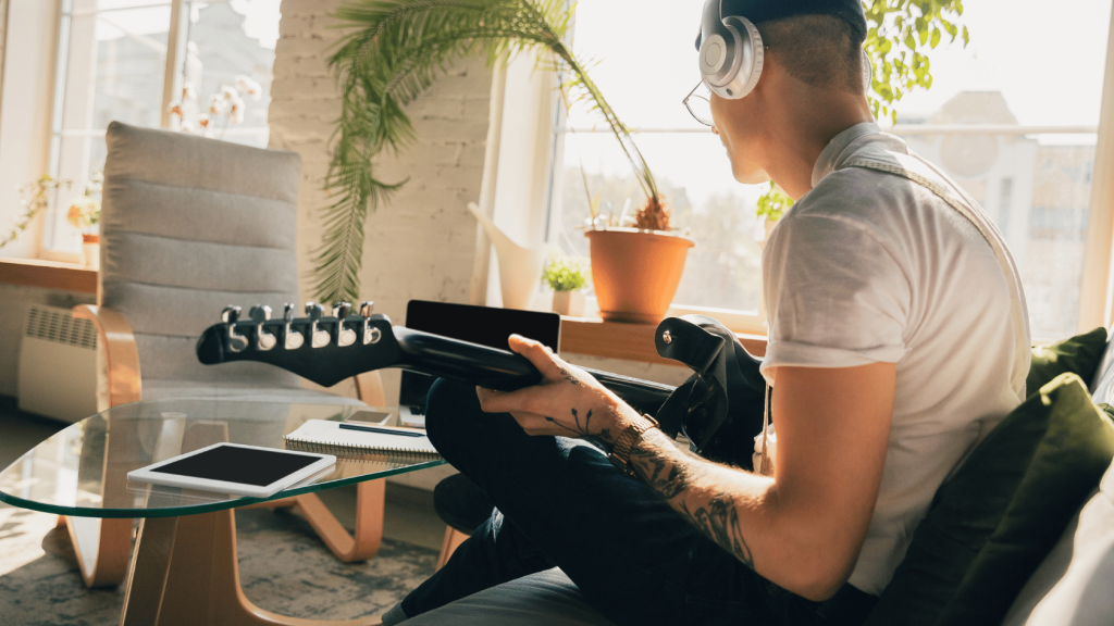 Guitar player with headphones and a laptop