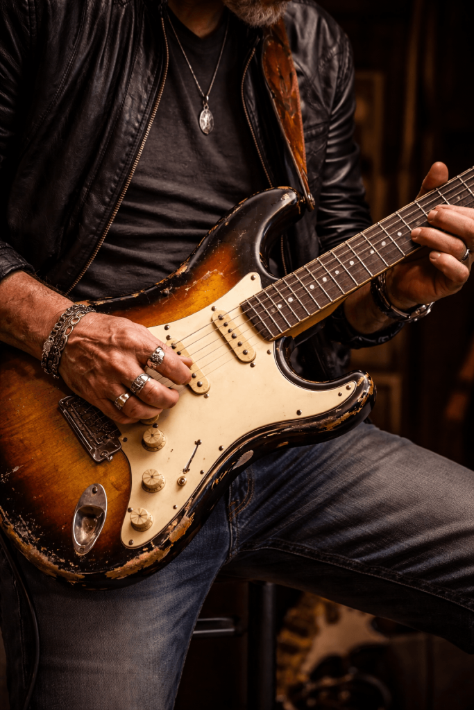 Guitar player playing a worn Stratocaster guitar
